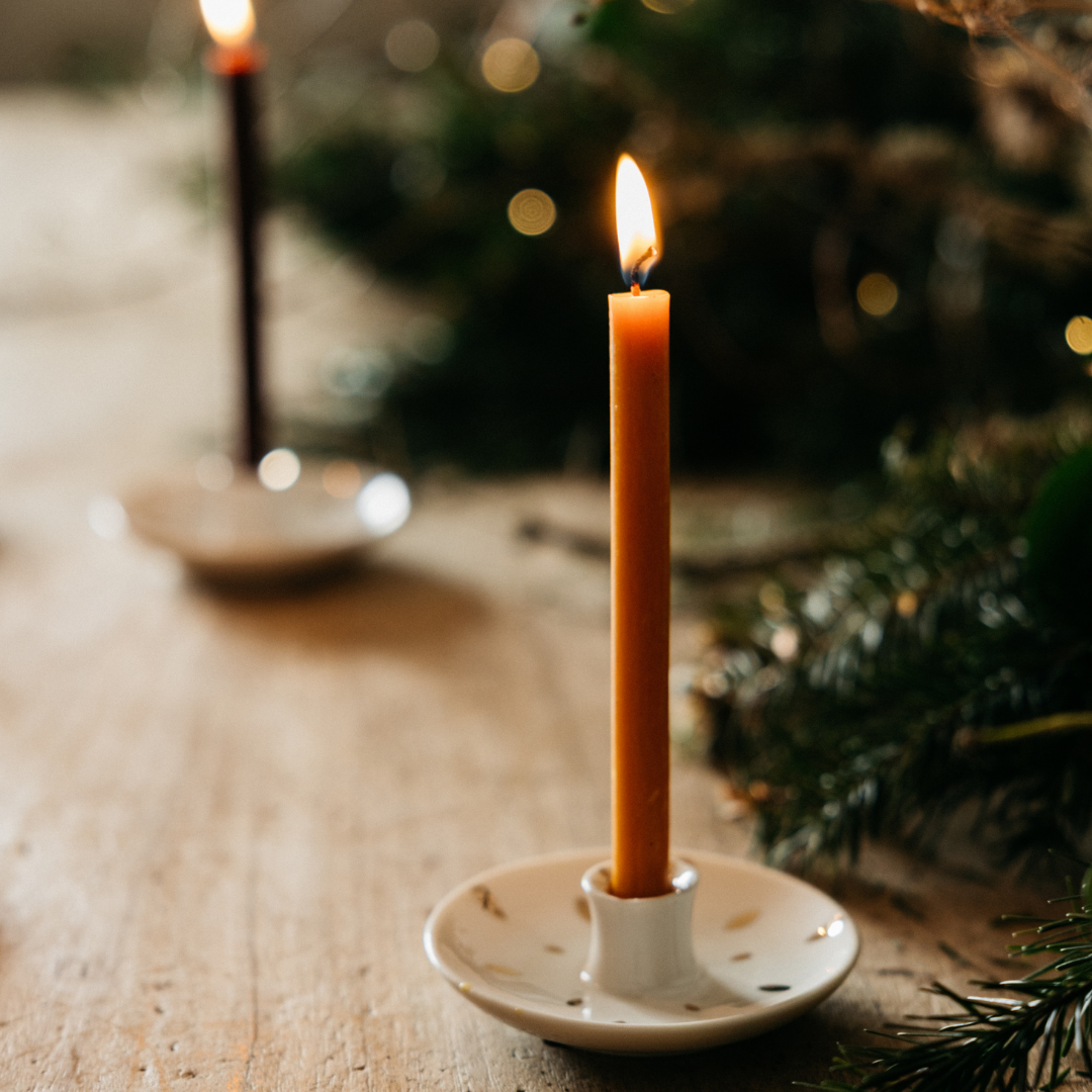 Orange & Cinnamon mini festive candle lit in a holder on a wooden table