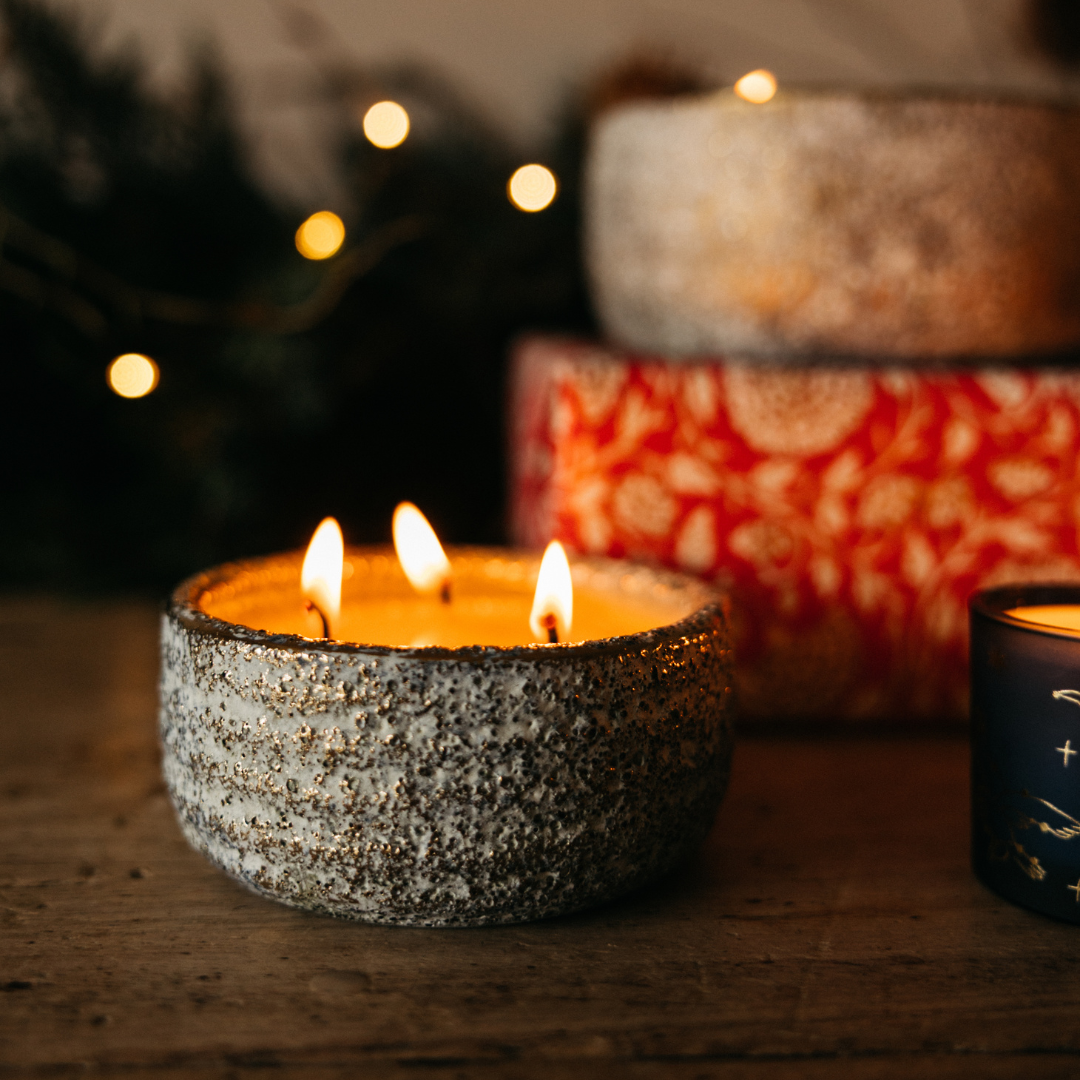 Orange & Cinnamon Small Alchemy Pot Candle lit with three flames in a cosy festive setting