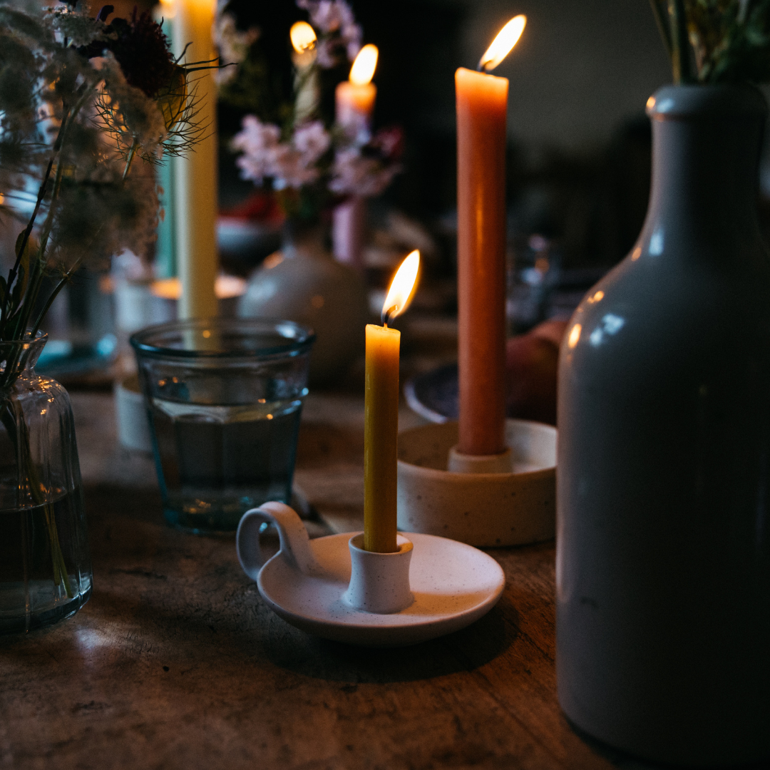 White Speckle candle holders with lit mini candles on a dark table