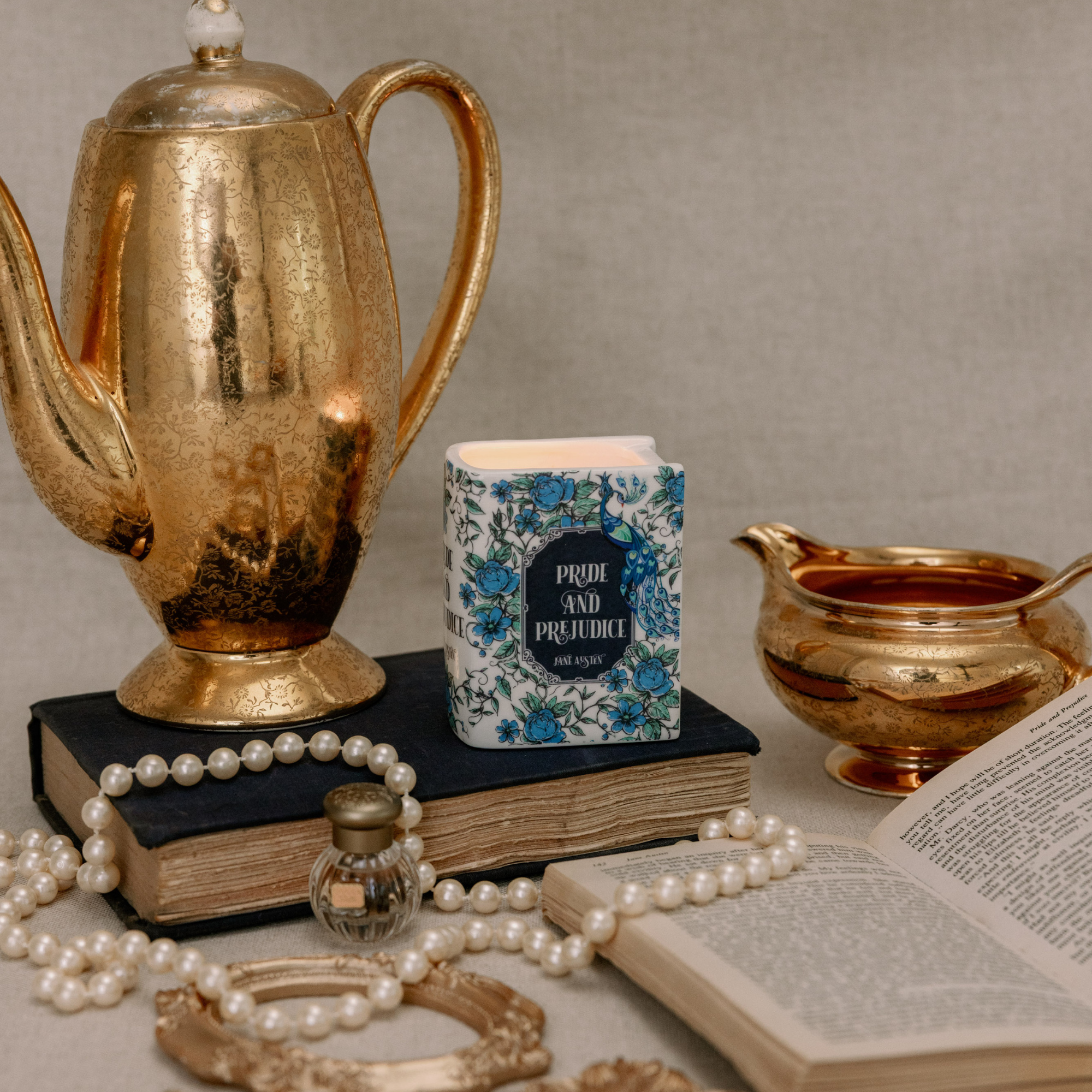 Book shaped candle shown next to gold teapot for scale in styled setting