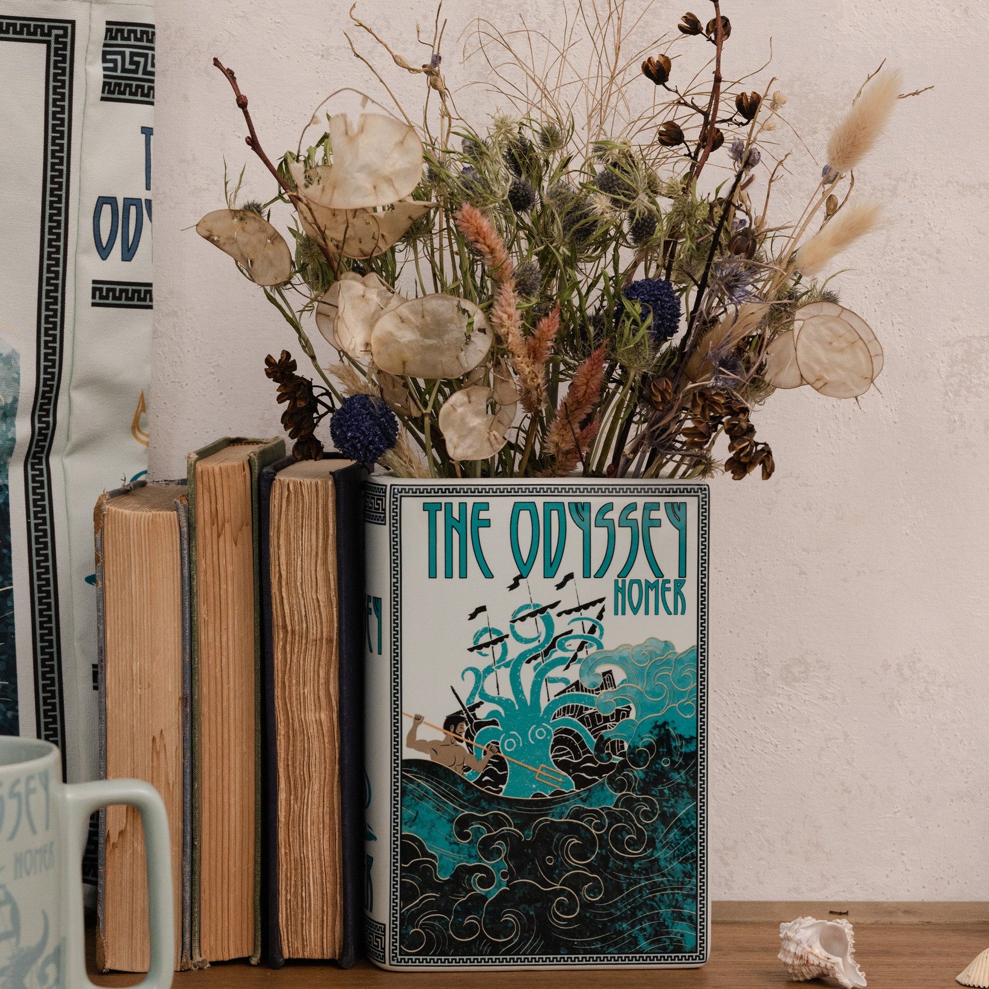 The Odyssey book vase holding dried flowers on a wooden surface