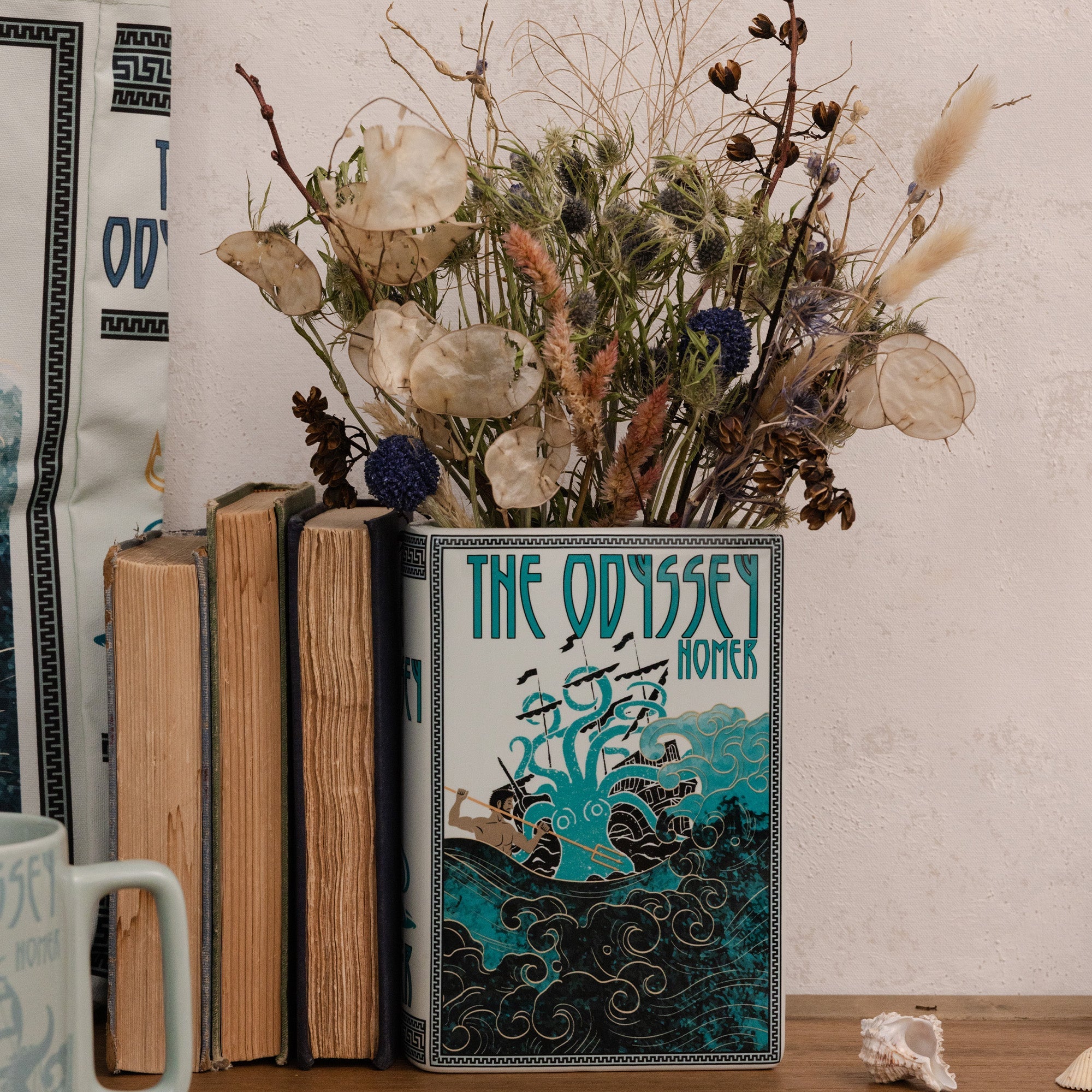 The Odyssey book vase holding dried flowers on a wooden surface