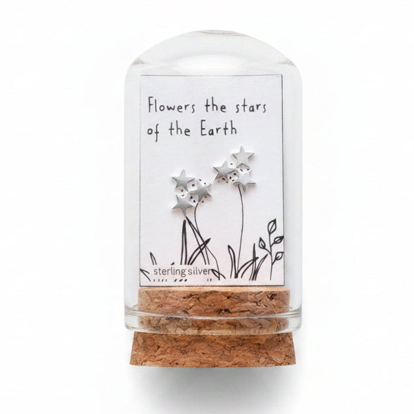 Small glass bottle with dried flowers and a label on a wooden surface