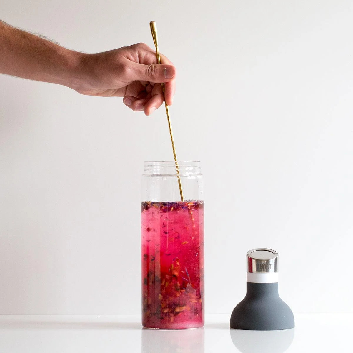 Mixing infused Strawberry Daiquiri with a gold cocktail stirrer.