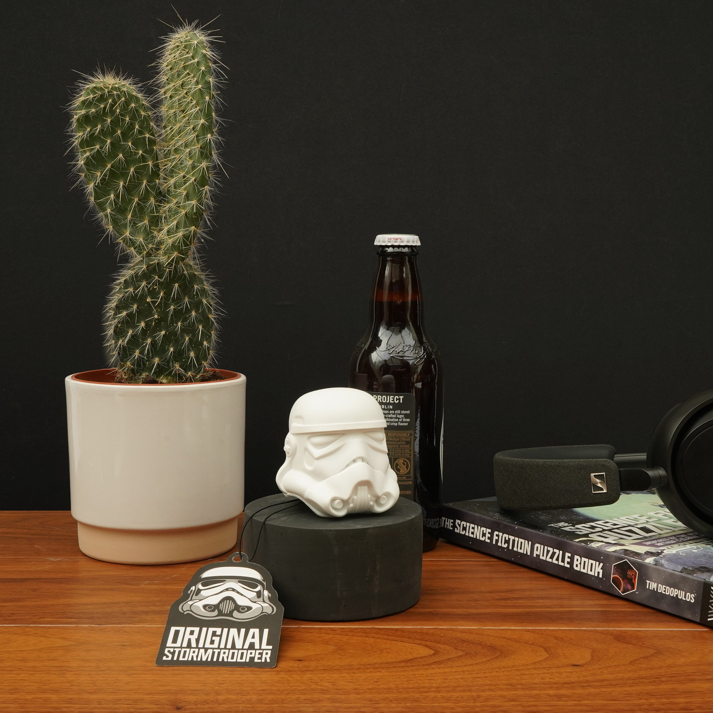 Stormtrooper bottle opener on a desk beside beer bottle, cactus and sci-fi books